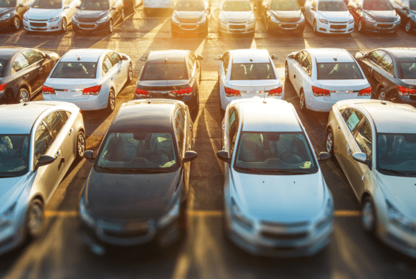 Aerial view of a parking lot filled with rows of parked cars in various colors, illuminated by warm sunlight. The cars are neatly arranged, echoing the precision and orderliness you'd expect from a top Melbourne Accounting Firm handling your finances. The image captures both symmetry and efficiency perfectly.