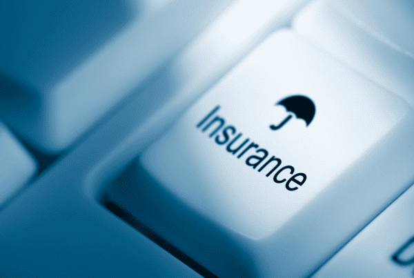 A close-up image of a computer keyboard with a white key labeled "Insurance" featuring an umbrella icon. The image, tinted with a blue hue, subtly emphasizes the relevance for Business Accountants navigating protection options.