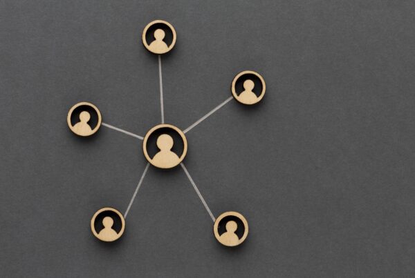 Wooden cutouts of five individuals are connected with strings, forming a network on a dark gray background. One central figure is linked to four surrounding figures, illustrating a hub-and-spoke model of connectivity—an apt metaphor for how our Melbourne Accounting Firm provides expert tax advice through your business accountants.