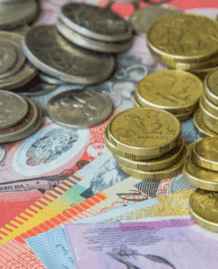 Several stacks of Australian coins and colorful Australian banknotes are spread out on a surface, showing various denominations and designs.