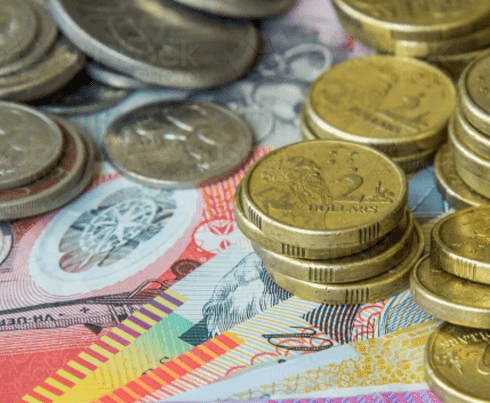 Several stacks of Australian coins and colorful Australian banknotes are spread out on a surface, showing various denominations and designs.